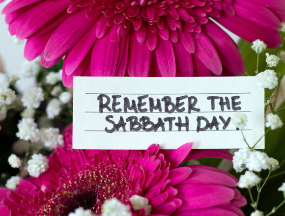 Remember the Sabbath Day, handwritten quote on paper with flowers. Close-up. Christian rest and obedience to God Jesus Christ, biblical concept.
