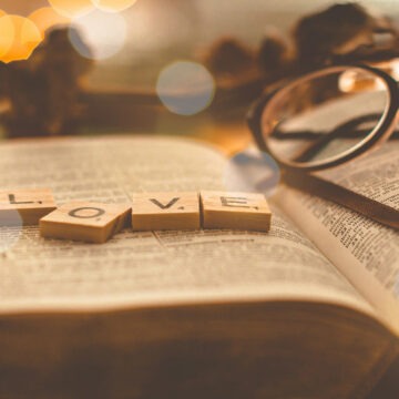 Steine mit der Aufschrift LOVE, die auf einer aufgeschlagenen Bibel liegen
