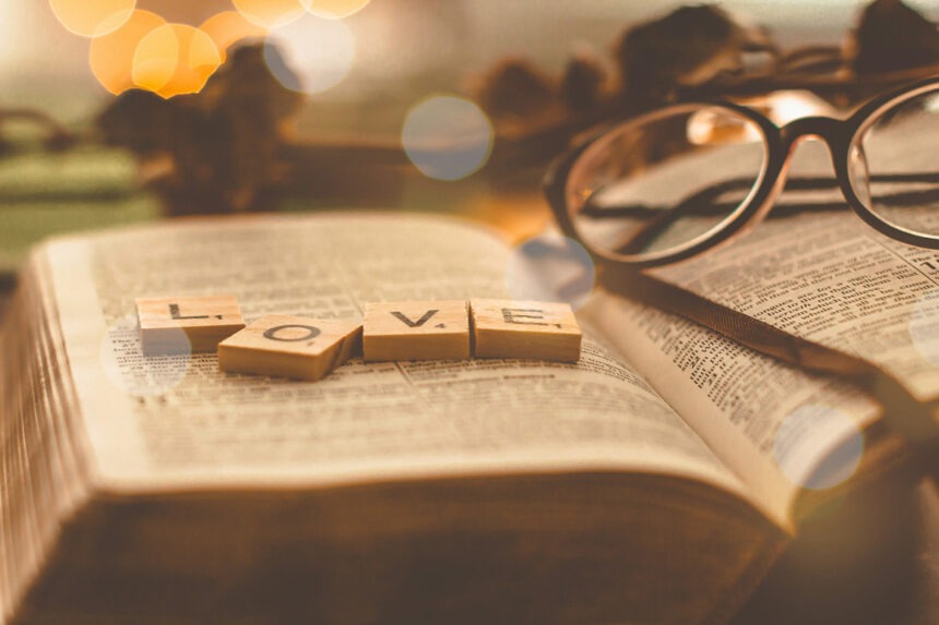 Steine mit der Aufschrift LOVE, die auf einer aufgeschlagenen Bibel liegen