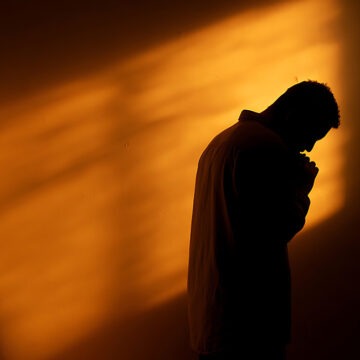 seelische-heilung Auf der Suche nach Hoffnung: Silhouette eines Mannes, der in schwierigen Zeiten um Führung und Kraft betet. Spiritualität und Glaube – Konzept für redaktionelle Zwecke, Blog-Inhalte und Sensibilisierung für psychische Gesundheit