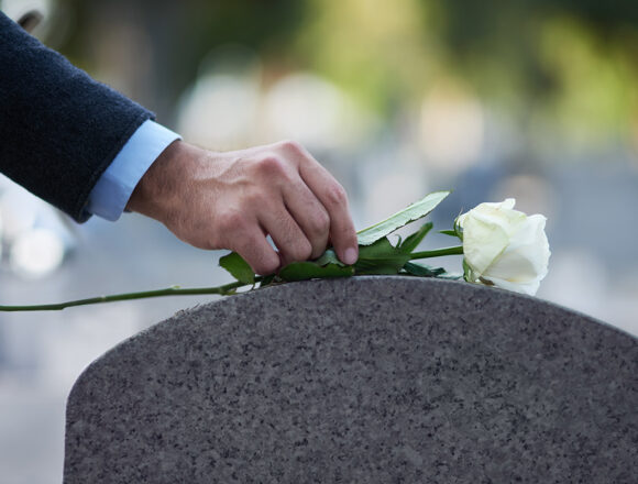 Grabstein Paying his respects. Cropped shot of a man placing a white rose on a grave.