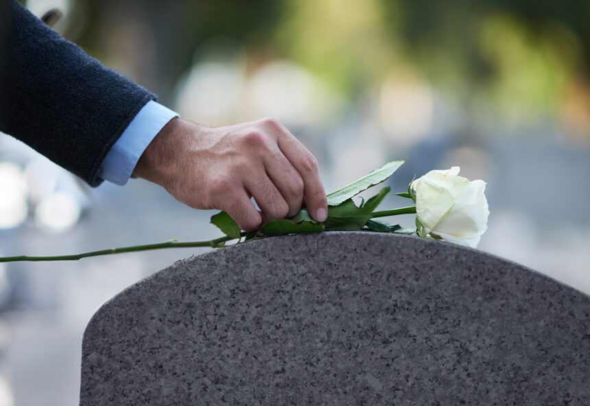 Grabstein Paying his respects. Cropped shot of a man placing a white rose on a grave.
