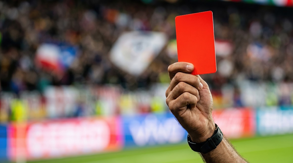 Ein Schiedsrichter zeigt in einem Fußballspiel eine rote Karte.