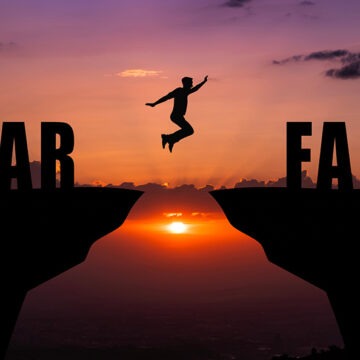 Overcoming Fear Through Faith—Taking the Step Toward Trust At sunset, a person leaps across a chasm from “Fear” to “Faith”—a symbol of trust in the face of fear.