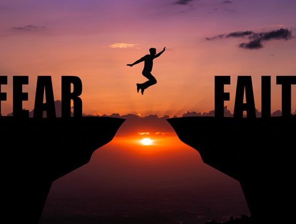 Overcoming Fear Through Faith—Taking the Step Toward Trust At sunset, a person leaps across a chasm from “Fear” to “Faith”—a symbol of trust in the face of fear.